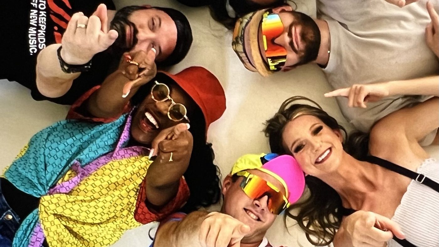 The All That & A Bag Of Chips cast in bright nineties outfits and sunglasses, crowding into the frame for a group photo.